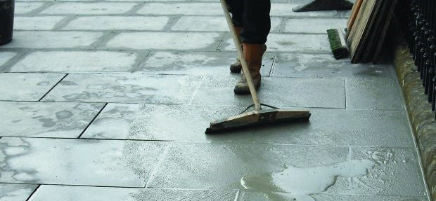 Applying Flowpoint Grout to paving slabs using a long-handled rubber squeegee