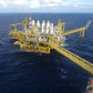 Offshore drill oil rig painted yellow, in dark blue ocean waters